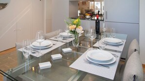 A dining table set with plates, glasses, and cutlery, with a vase of flowers in the center. - Tasman S12/R by Interhome (Le Bouveret)