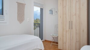 A bedroom with a bed, a wooden wardrobe, a small table with a chair, a round mirror, and a macrame wall hanging. - Tasman S12/R by Interhome (Le Bouveret)