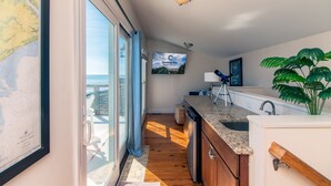 A kitchen with a wooden floor, a sink, a countertop, and a large potted plant. - Moon Tide|Oceanfront Showplace|Dog Friendly|Elevator|Rooftop Deck|Family-Friendly Amenities (Edisto Beach)