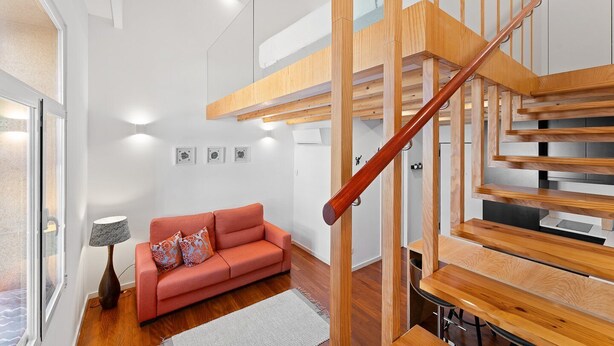 Un intérieur moderne avec un escalier en bois, un canapé rouge et une lampe.