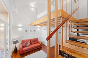 En modern inredning med en trätrappa, en röd soffa och en lampa.