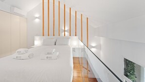 Une chambre d’hôtel moderne avec un grand lit, des lambris en bois au mur et un escalier en verre.