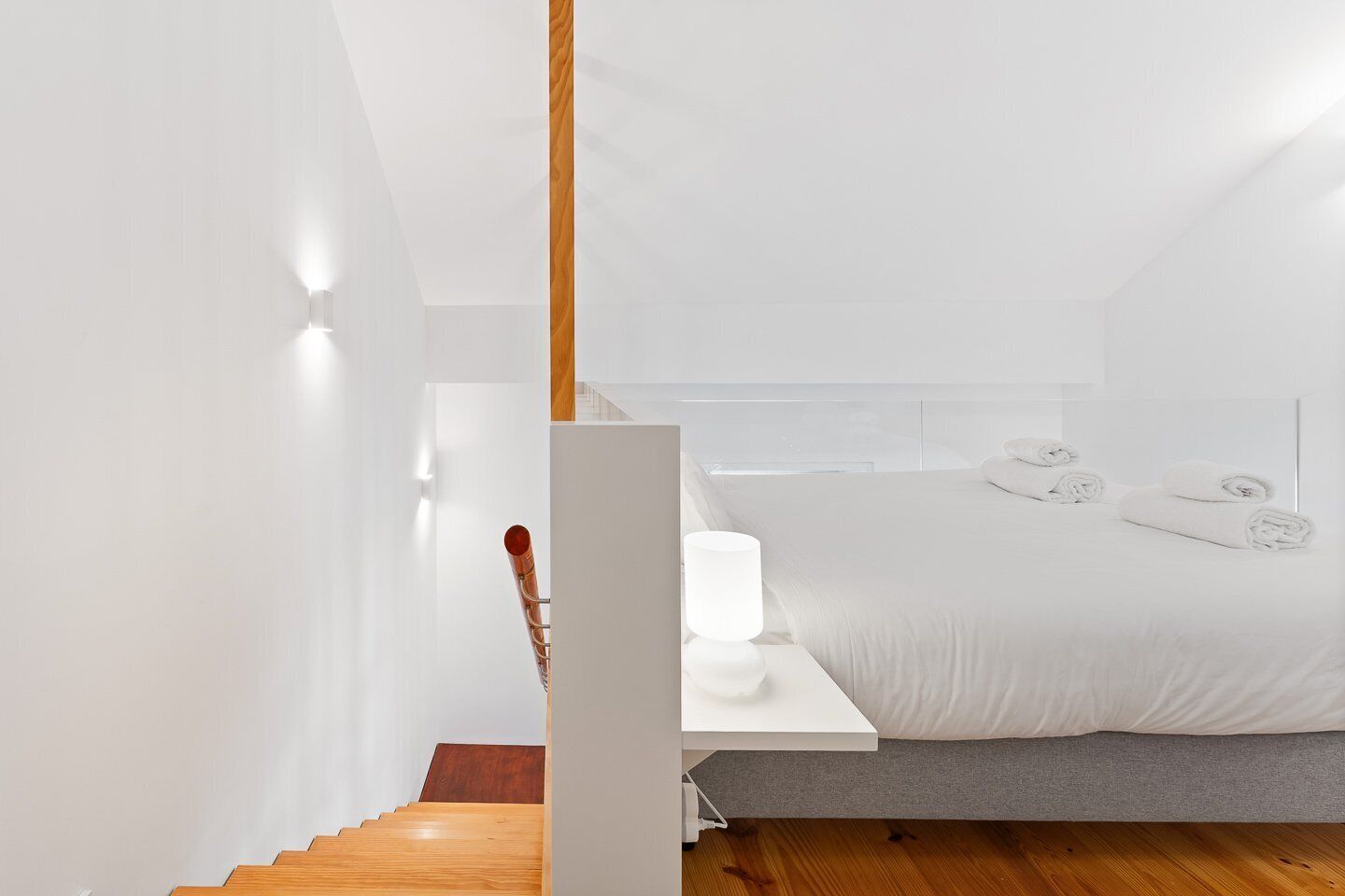 Un dormitorio moderno con cama, mesita de noche y una escalera de madera.