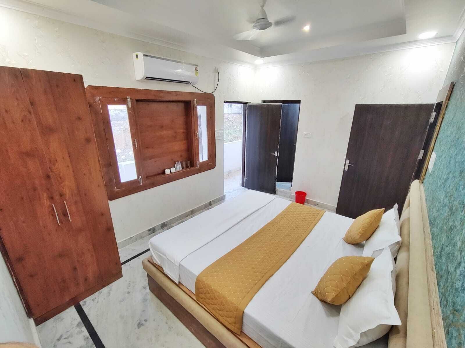 A bedroom with a bed, wooden wardrobe, and a window with a view.