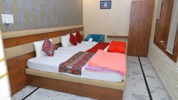 Habitación individual con una cama de madera, un edredón estampado y varias almohadas.