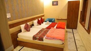 Una habitación de hotel con una cama grande, dos almohadas, una colcha y una mesita con una silla.