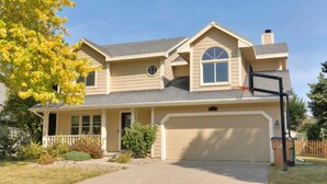 A two-story house with a garage, a basketball hoop, and a well-maintained lawn. - Modern Comfort in Des Moines` West Side 4BR/2.5BR (Clive)