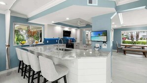 Une cuisine moderne dotée d’un grand îlot central, de tabourets de bar et d’un coin repas avec une banquette.