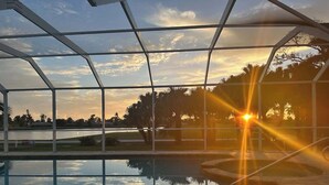 Un espace piscine abrité offrant une vue dégagée sur le coucher de soleil et le paysage environnant.
