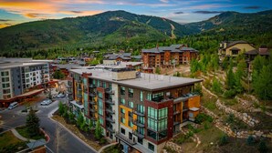 A modern multi-story hotel with a mix of balconies and large windows, surrounded by a mountainous landscape.