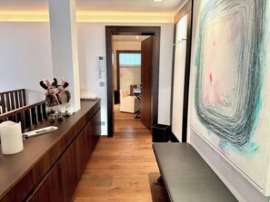 Un espace d’accueil avec un comptoir en bois, une grande peinture abstraite et un couloir menant à une pièce dotée d’une fenêtre.