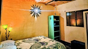 A bedroom with a bed, a ceiling fan, a decorative light fixture, and a window with a view of the outside.