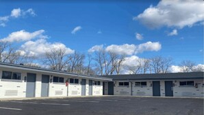 Una fila di edifici motel a piano terra, con un parcheggio di fronte.