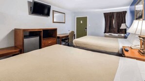Camera d'albergo con due letti, una scrivania, una sedia, una televisione, uno specchio e una finestra con tende.