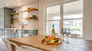 Eine moderne Küche mit Holzböden, einem großen Fenster und einem Esstisch, gedeckt mit Speisen und Weingläsern.