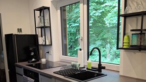 A modern kitchen with a built-in stove, a sink, and a window overlooking greenery. - Allgäu vacation apartment 2 adults + 2 children Kempten-Rothkreuz in the countryside (Kempten (Allgäu))