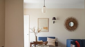 A dining room with a table, chairs, a ceiling fan, a vase with fruit, a lamp, and a mirror.