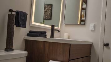 Une salle de bain moderne équipée de toilettes, d’un meuble-lavabo et de miroirs.
