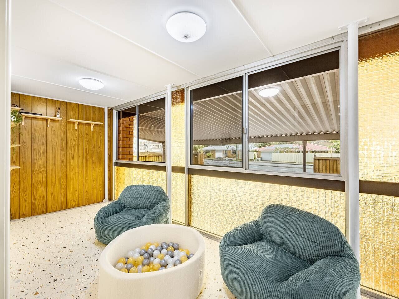 A room with two green chairs, a white bean bag, and a bowl of balls.