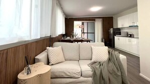 Een moderne woonkamer met een bank, een klein bijzettafeltje en uitzicht op de keuken.