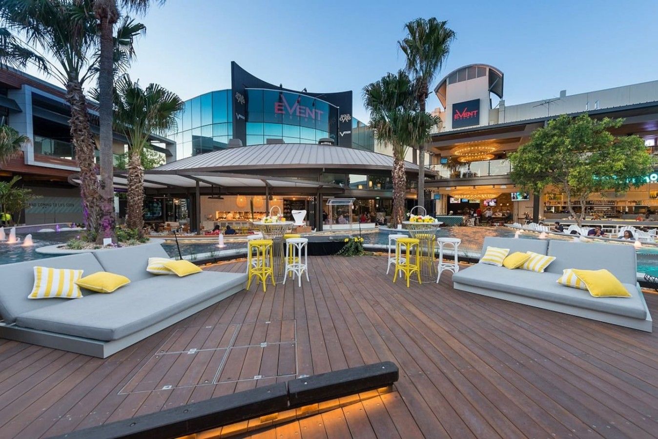 A rooftop bar with seating areas, a pool, and a modern building with 'EVENT' signage.