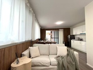 Un salon moderne avec un canapé, une petite table d’appoint et une vue sur la cuisine.