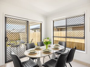 A dining area with a round table, black chairs, and a vase of flowers.