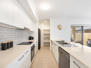 A modern kitchen with white cabinets, a black refrigerator, and a beige countertop.