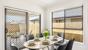 Een eethoek met een ronde tafel, zwarte stoelen en een bloevas.
