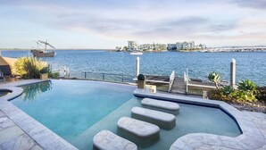 Una piscina con vista al agua y edificios al fondo.