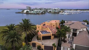 Una propiedad costera con varias construcciones, un puerto deportivo y palmeras.