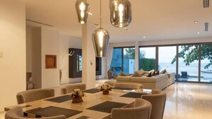 A modern living room with a large dining table, sofas, and pendant lighting. - Beachfront Villa 3BR Infinity Pool V38 (Rawai)