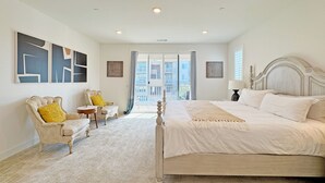 A bedroom with a large bed, two armchairs, a small table, and artwork on the walls. - Fabulous 4-bedroom house with AC in irvine Lake Forest (Lake Forest)