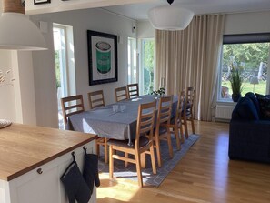 A dining area with a table set for four, wooden chairs, a grey tablecloth, and a framed picture on the wall.