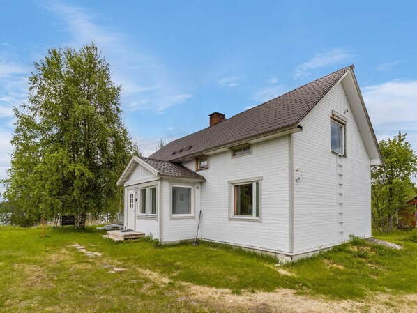A single-story white house with a gabled roof, a front porch, and a small deck.