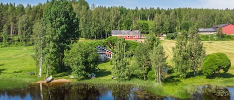 A lakeside property with a red house, a smaller white house, and a red barn.