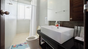 A bathroom with a white sink, a toilet, a shower, and a mirror.