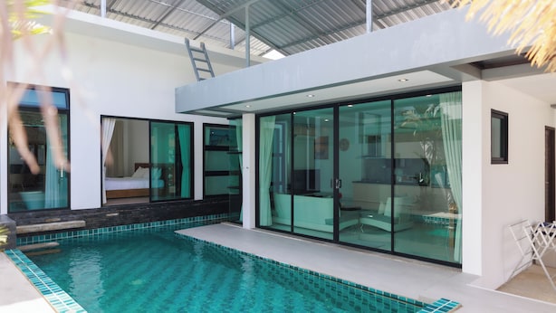 A modern house with a swimming pool, large glass doors, and a covered patio area.