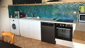 A compact kitchen with a washing machine, dishwasher, and a built-in oven.