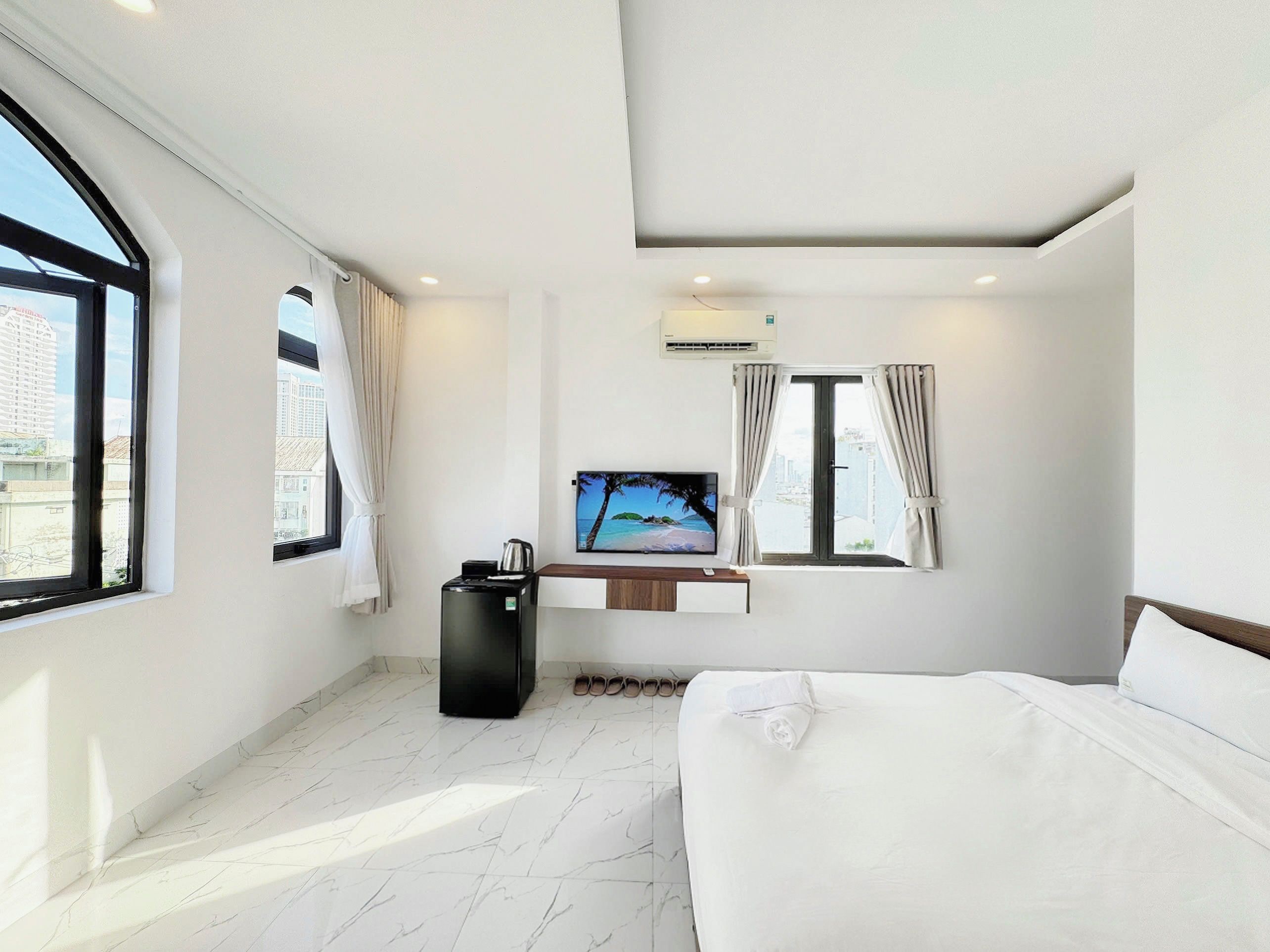 A hotel room with a bed, a desk with a computer, a coffee maker, and a TV.
