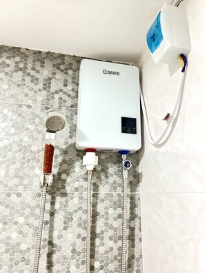 A water heater with a digital display, connected to a white wall with hexagonal tiles.