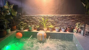 Ein kleiner Innenpool mit Steinwand im Hintergrund, umgeben von Topfpflanzen.