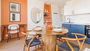 A dining area with a round wooden table, six chairs, and a fruit basket. - Luminous Apartment - Saint Germain des Pres (Paris)