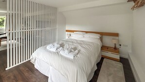 A bedroom with a bed, bedside table, lamp, and a view through a window. - 1 bedroom accommodation in Horsham, near Brighton (Horsham, near Brighton)