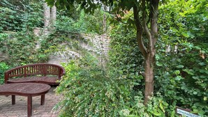A wooden bench and table set on a brick-paved area with lush greenery and a sign reading 'Shepherds Loft'. - 1 bedroom accommodation in Horsham, near Brighton (Horsham, near Brighton)