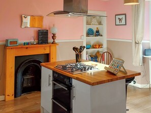 A kitchen with a gas stove, oven, and a wooden island.