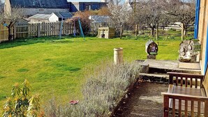 Un jardin résidentiel avec une pelouse, une balançoire, une clôture en bois et une serre.