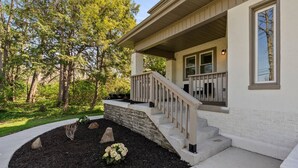 A house with a stone retaining wall, a wooden staircase, and a landscaped garden with mulch and rocks.