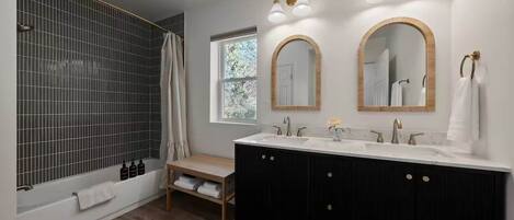 A modern bathroom with a bathtub, a vanity with two sinks, and three mirrors.
