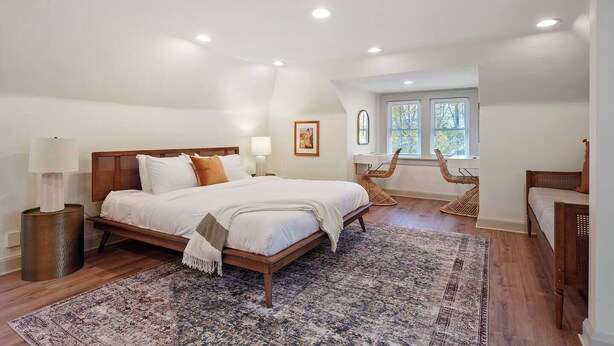 A spacious bedroom with a large bed, two bedside tables, a window, and a built-in desk with chairs. - Close to OSU Rooftop Patio  Grill & Outdoor TV (Columbus)